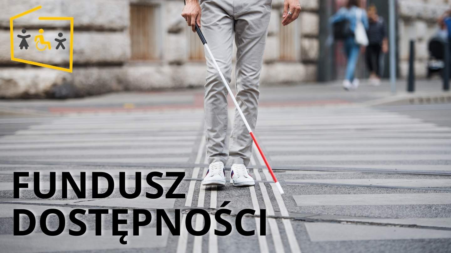 osoba niewidoma z białą laską na mieście, napis Fundusz Dostępności i logo Programy Dostępność Plus